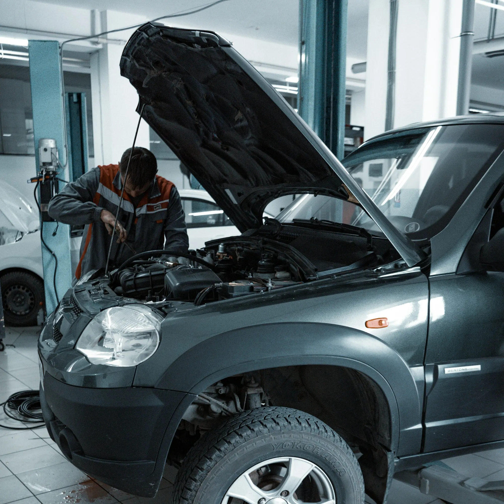 Car with its hood raised inside a repair bay