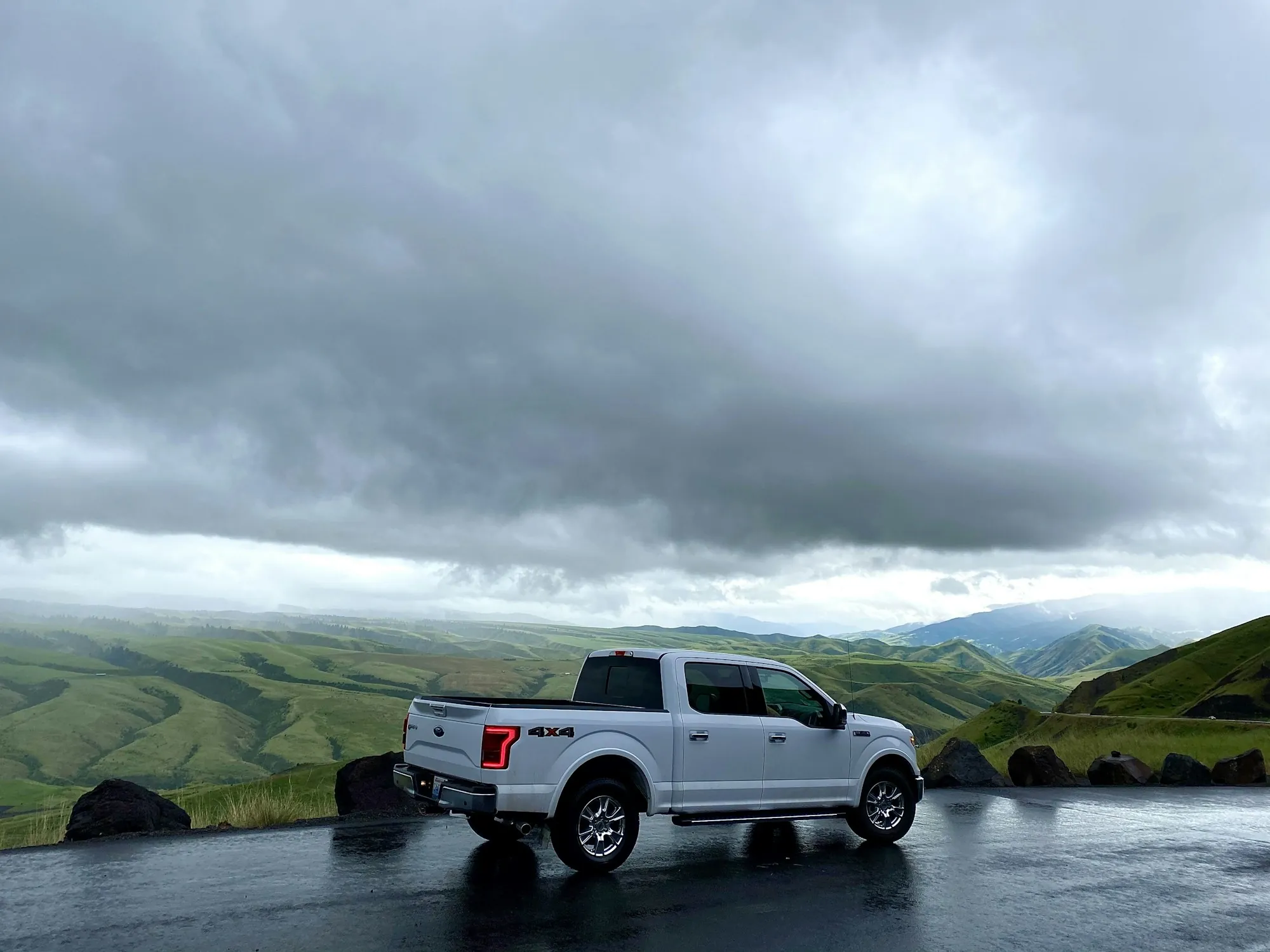 Pickup truck parked below a mountain ridge on a cloudy day