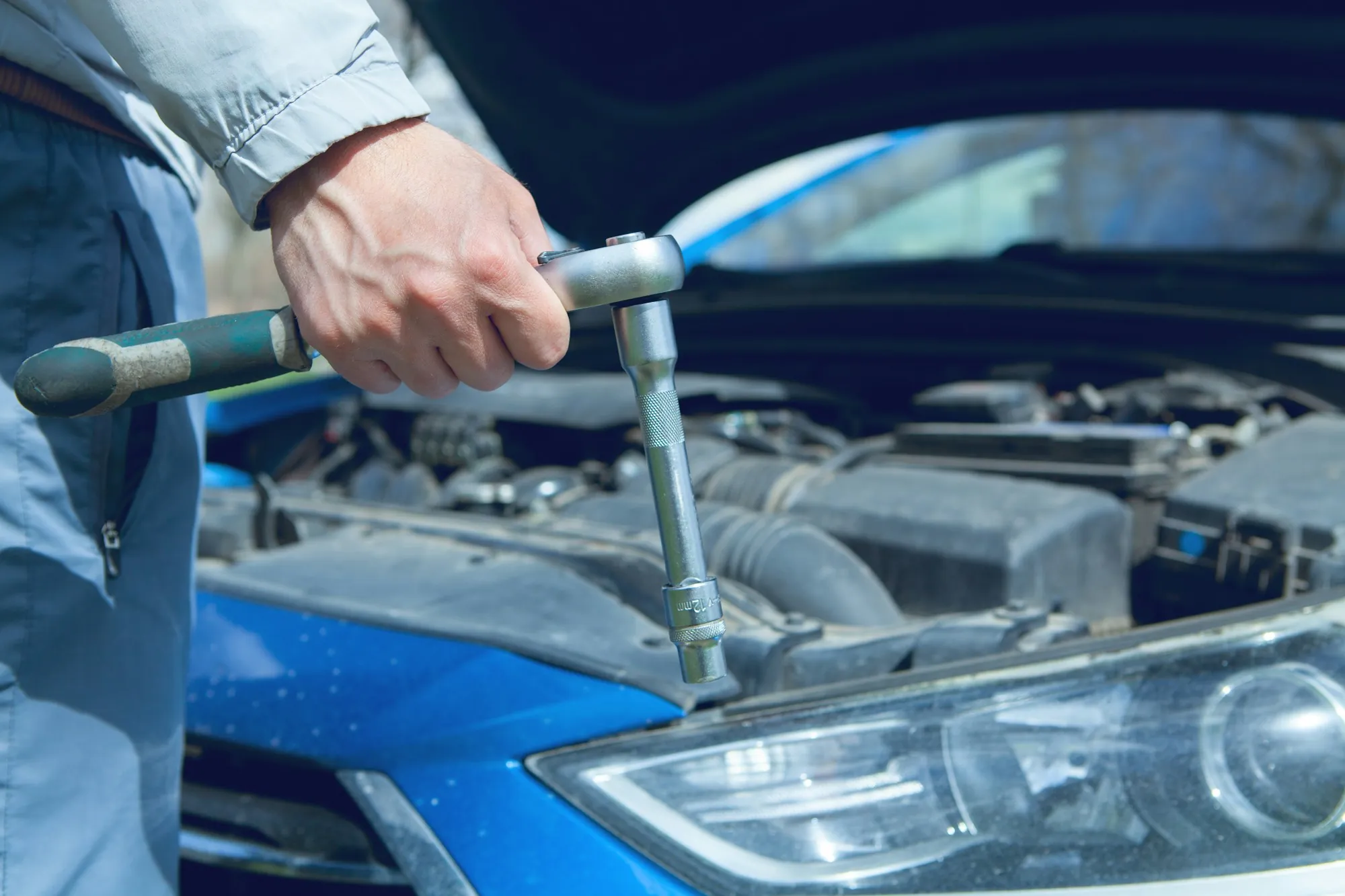 Technician working on a vehicle with tools in hand