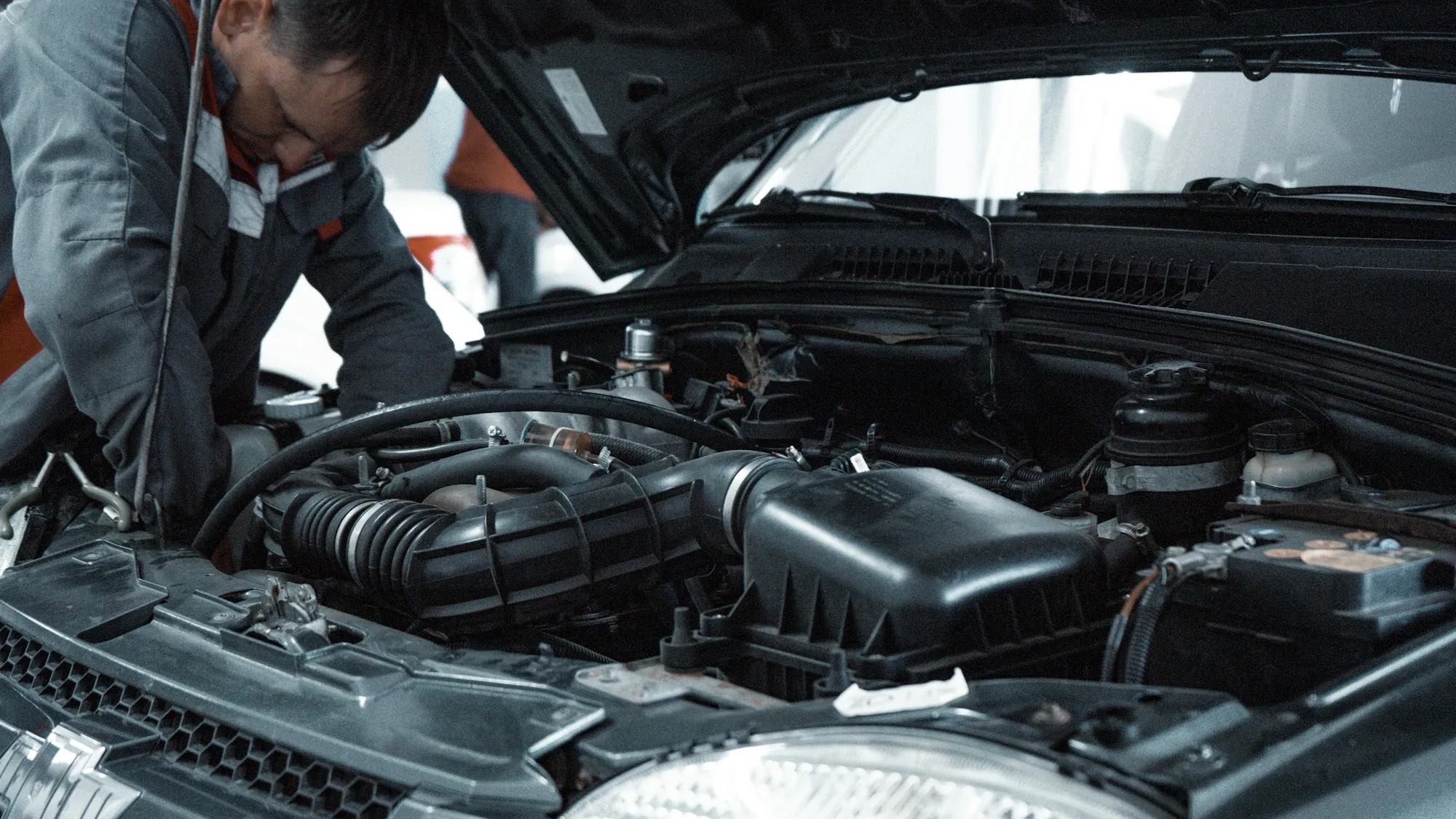 Two technicians leaning over an open engine bay