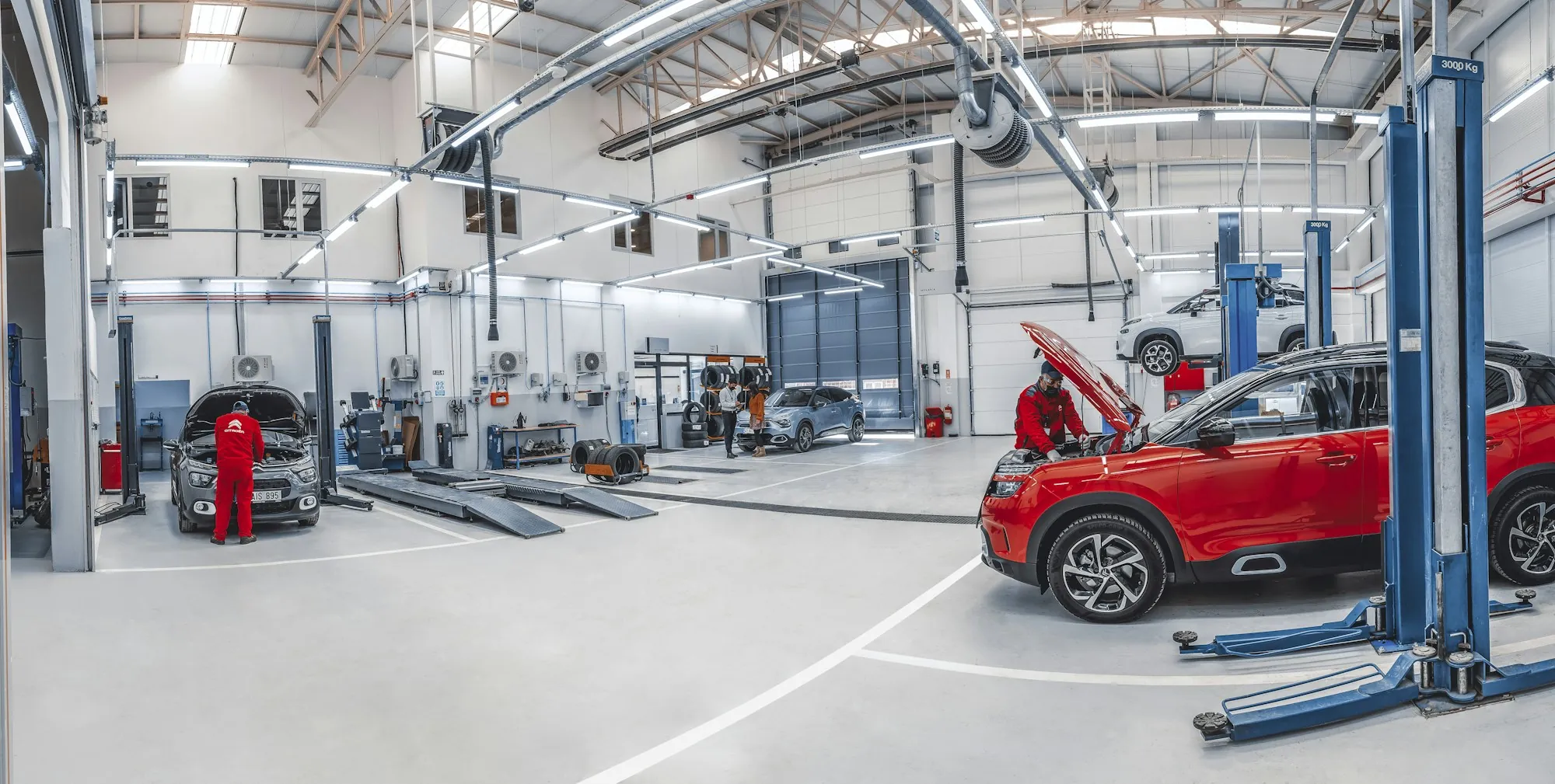 Clean, bright repair shop with a red SUV raised on a lift